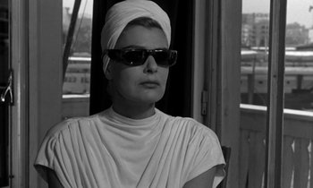 Movie still from “Phaedra” (1962), directed by Jules Dassin – A woman wearing a head scarf and sunglasses; Close Up shot, Low angle