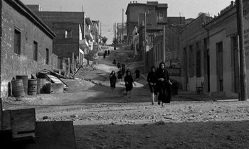 Movie still from “Phaedra” (1962), directed by Jules Dassin – A black and white photo of people walking down a street; Extreme Wide shot, High angle