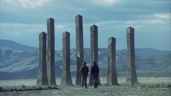 Movie still from “Phase IV” (1974), directed by Saul Bass – Two men are standing in front of a group of tall stone pillars; Extreme Wide shot, Low angle