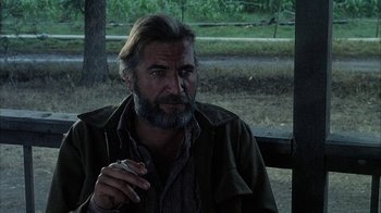 Movie still from “Phase IV” (1974), directed by Saul Bass – A man sitting on a wooden bench smoking a cigarette; Close Up shot, Over the shoulder angle