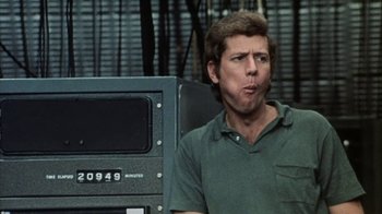 Movie still from “Phase IV” (1974), directed by Saul Bass – A man in a green shirt is sitting in front of a television; Close Up shot, Over the shoulder angle