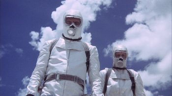 Movie still from “Phase IV” (1974), directed by Saul Bass – Two people in white suits and gas masks; Medium shot, Low angle