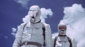 Movie still from “Phase IV” (1974), directed by Saul Bass – Two people in white suits and gas masks; Medium shot, Low angle