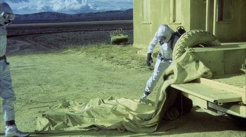 Movie still from “Phase IV” (1974), directed by Saul Bass – A man in a spacesuit is sitting on a bench; Wide shot, Low angle