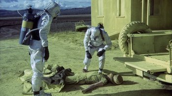 Movie still from “Phase IV” (1974), directed by Saul Bass – Two people in full hazmat suits looking at a dead body; Wide shot, High angle