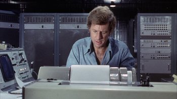Movie still from “Phase IV” (1974), directed by Saul Bass – A man sitting in front of a laptop computer; Close Up shot, Low angle