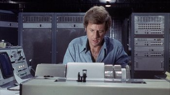 Movie still from “Phase IV” (1974), directed by Saul Bass – A man sitting in front of a laptop computer; Close Up shot, Low angle