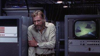 Movie still from “Phase IV” (1974), directed by Saul Bass – A man with a beard and a watch is leaning against a wall; Medium shot, Low angle