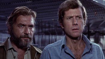 Movie still from “Phase IV” (1974), directed by Saul Bass – Two men standing next to each other in front of a building; Close Up shot, Low angle