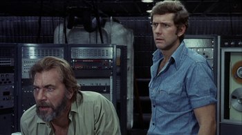 Movie still from “Phase IV” (1974), directed by Saul Bass – A man in a blue shirt and a man in a green shirt; Medium shot, Low angle