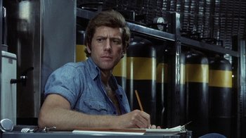 Movie still from “Phase IV” (1974), directed by Saul Bass – A man sitting at a table writing on a piece of paper; Close Up shot, Low angle