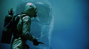 Movie still from “Phase IV” (1974), directed by Saul Bass – A man in a scuba suit pointing to a mask; Medium shot, Low angle