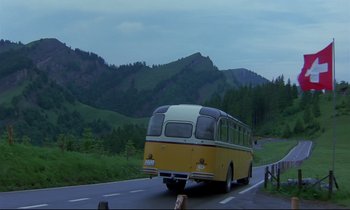 Movie still from “Phenomena” (1985), directed by Dario Argento – A yellow and white bus driving down a road; Extreme Wide shot, Low angle