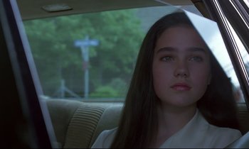 Movie still from “Phenomena” (1985), directed by Dario Argento – A young woman sitting in a car looking out the window; Close Up shot, Over the shoulder angle