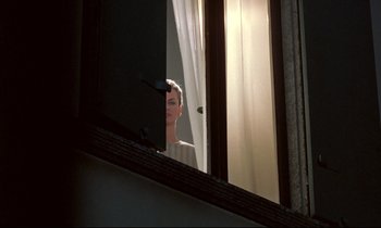 Movie still from “Phenomena” (1985), directed by Dario Argento – A man looking out of a window at the sun through the blinds; Wide shot, Low angle