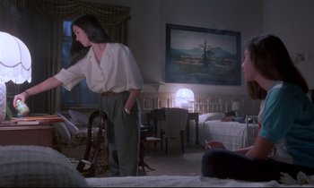 Movie still from “Phenomena” (1985), directed by Dario Argento – A woman standing in front of a painting in a living room; Medium shot, Low angle