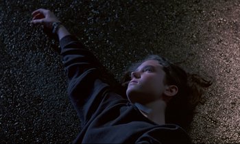 Movie still from “Phenomena” (1985), directed by Dario Argento – A person laying on the ground in the dark; Medium shot, Overhead angle