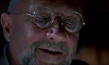 Movie still from “Phenomena” (1985), directed by Dario Argento – An older man wearing glasses and a beard; Extreme Close Up shot, Low angle