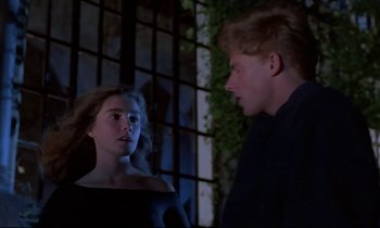 Movie still from “Phenomena” (1985), directed by Dario Argento – A man and a woman standing next to each other in front of a window; Medium shot, Over the shoulder angle