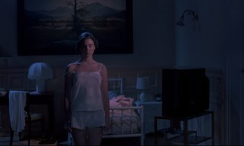 Movie still from “Phenomena” (1985), directed by Dario Argento – A woman standing in the dark in front of a painting; Wide shot, High angle
