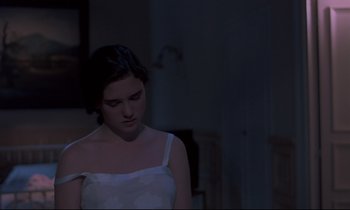 Movie still from “Phenomena” (1985), directed by Dario Argento – A woman in a white dress is looking down at the floor; Medium shot, Over the shoulder angle