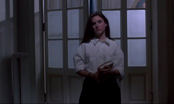 Movie still from “Phenomena” (1985), directed by Dario Argento – A woman in a white shirt holding a book in her hands; Medium shot, Low angle