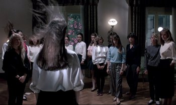 Movie still from “Phenomena” (1985), directed by Dario Argento – A group of people standing in a room; Wide shot, High angle
