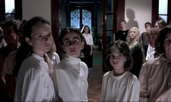 Movie still from “Phenomena” (1985), directed by Dario Argento – A group of young women standing next to each other in a room; Medium shot, Low angle