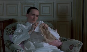 Movie still from “Phenomena” (1985), directed by Dario Argento – A woman in a white robe is knitting a blanket; Close Up shot, High angle