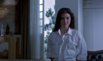 Movie still from “Phenomena” (1985), directed by Dario Argento – A woman in a white shirt standing in front of a window; Medium shot, Over the shoulder angle