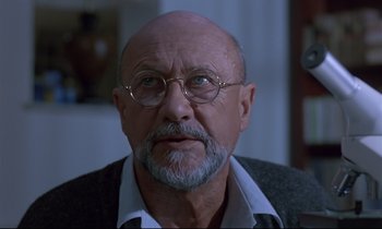 Movie still from “Phenomena” (1985), directed by Dario Argento – An older man with a beard and glasses; Close Up shot, Over the shoulder angle