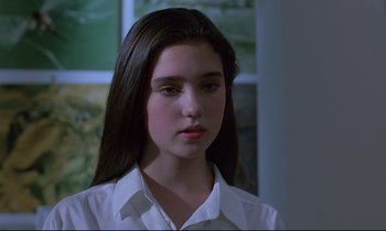 Movie still from “Phenomena” (1985), directed by Dario Argento – A young woman with long hair wearing a white shirt; Close Up shot, High angle