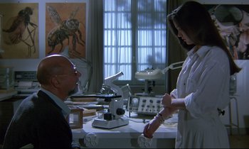 Movie still from “Phenomena” (1985), directed by Dario Argento – A man and a woman in a lab setting; Medium shot, Low angle