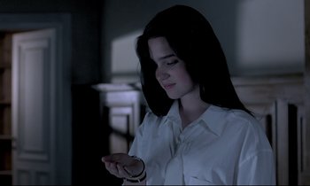 Movie still from “Phenomena” (1985), directed by Dario Argento – A woman in a white shirt is looking at her cell phone; Close Up shot, Low angle