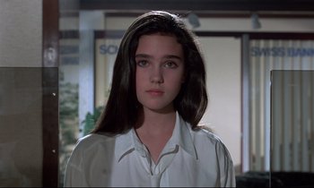 Movie still from “Phenomena” (1985), directed by Dario Argento – A woman with long black hair wearing a white shirt; Close Up shot, Over the shoulder angle