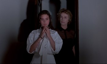 Movie still from “Phenomena” (1985), directed by Dario Argento – Two young women standing next to each other in front of a mirror; Medium shot, Low angle