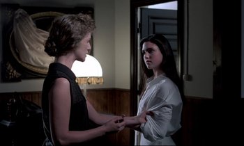 Movie still from “Phenomena” (1985), directed by Dario Argento – Two young women standing next to each other in a room; Medium shot, Over the shoulder angle