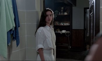 Movie still from “Phenomena” (1985), directed by Dario Argento – A young woman standing in front of a phone; Medium shot, Low angle