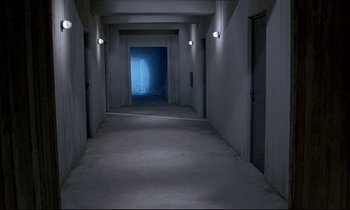 Movie still from “Phenomena” (1985), directed by Dario Argento – A hallway with a door open and a light on the wall; Extreme Wide shot, High angle