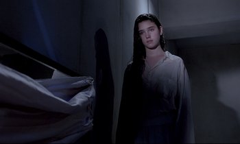 Movie still from “Phenomena” (1985), directed by Dario Argento – A woman standing in a dark room next to a bed; Medium shot, Low angle