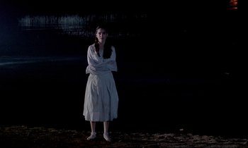 Movie still from “Phenomena” (1985), directed by Dario Argento – A woman standing in the dark with her arms crossed; Wide shot, Low angle