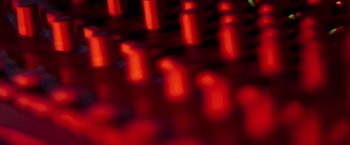 Movie still from “Songs for While I'm Away” (2020), directed by Emer Reynolds – A blurry image of a red candle lit fire; Extreme Close Up shot, Low angle