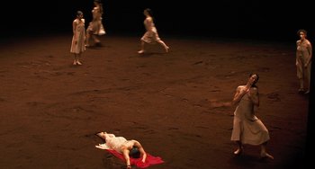 Movie still from “Pina” (2011), directed by Wim Wenders – A group of people standing on the ground in the dark; Extreme Wide shot, High angle