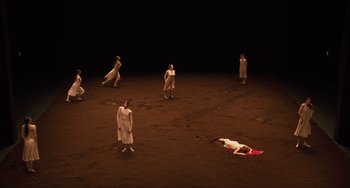 Movie still from “Pina” (2011), directed by Wim Wenders – A group of people standing on a dirt field; Extreme Wide shot, High angle