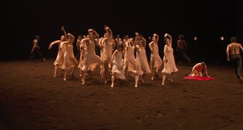 Movie still from “Pina” (2011), directed by Wim Wenders – A group of women in white dresses dancing on a dirt field; Extreme Wide shot, High angle