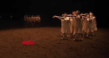 Movie still from “Pina” (2011), directed by Wim Wenders – A group of people standing on a dirt field; Extreme Wide shot, High angle