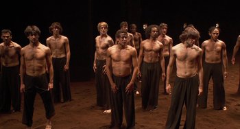 Movie still from “Pina” (2011), directed by Wim Wenders – A group of shirtless men standing next to each other; Wide shot, High angle
