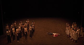 Movie still from “Pina” (2011), directed by Wim Wenders – A group of people standing around a man laying on the ground; Extreme Wide shot, High angle