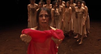 Movie still from “Pina” (2011), directed by Wim Wenders – A group of women standing in front of a woman in a red dress; Medium shot, High angle