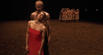 Movie still from “Pina” (2011), directed by Wim Wenders – A couple of people standing next to each other on a dirt field; Wide shot, High angle